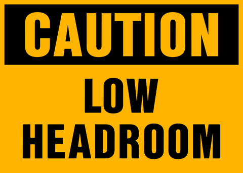A yellow sign with black text saying 'CAUTION LOW HEADROOM'.