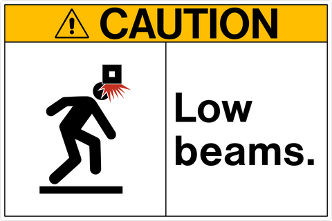 Safety sign with a pictogram depicting a person with a caution sign above their head saying 'CAUTION' and text underneath reading 'LOW BEAMS.'.