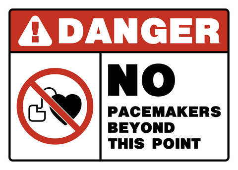 A warning sign with a red and white border, featuring the text 'DANGER' and a prohibition symbol over a heart, indicating no pacemakers beyond this point.